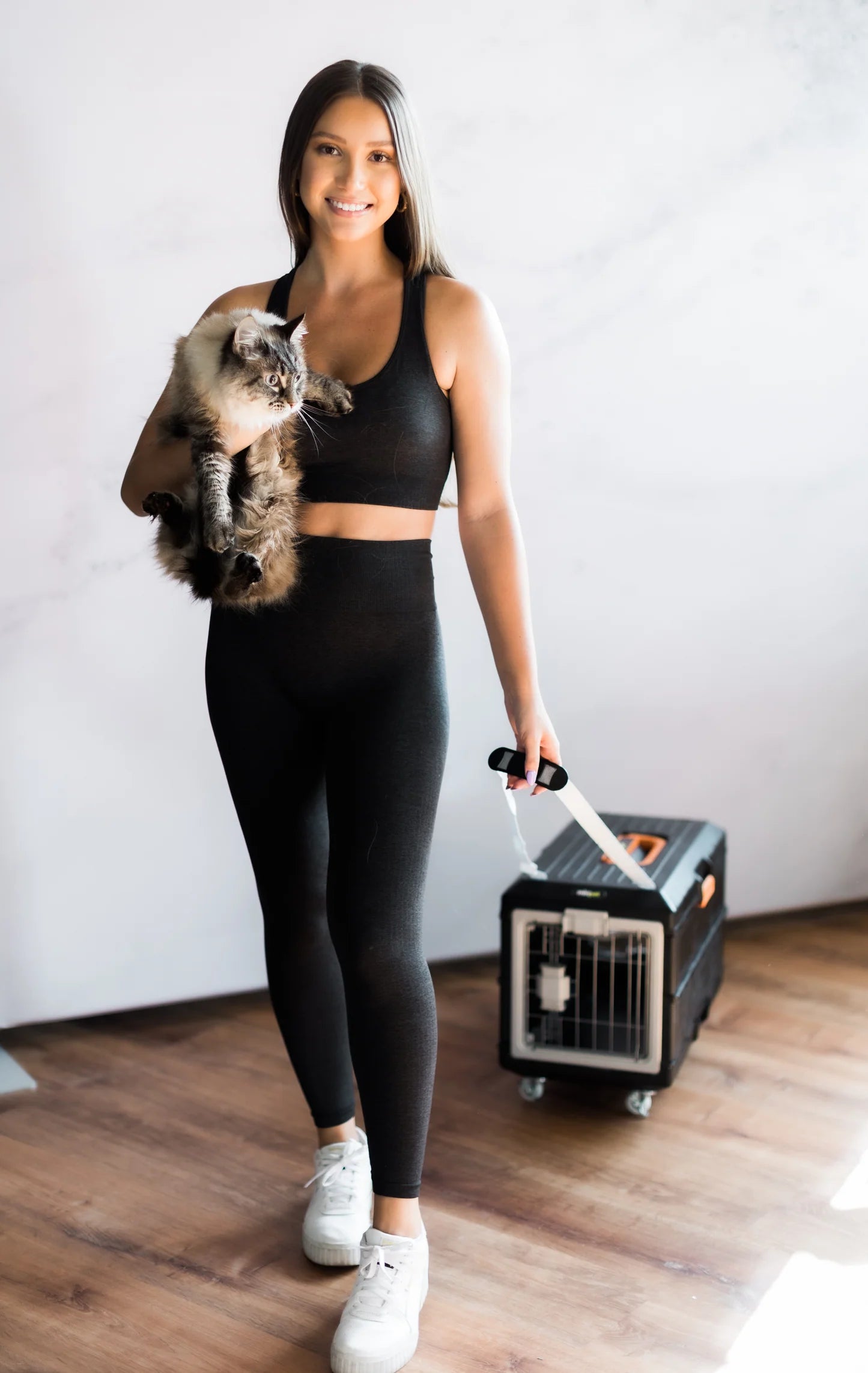 Woman holding a cat while easily pulling a travel dog crate on wheels.